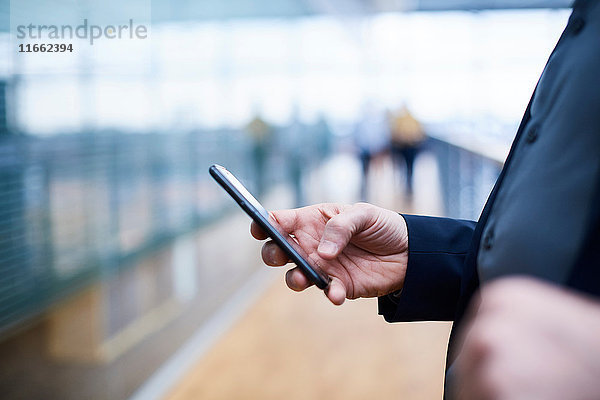 Nahaufnahme eines Geschäftsmannes mit Smartphone auf dem Bürobalkon