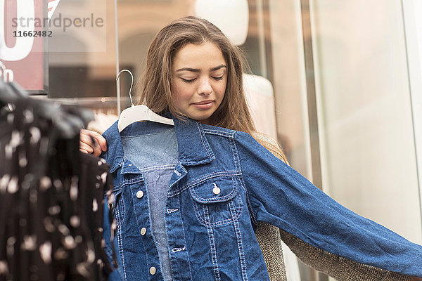 Junge Frau probiert Jeansjacke am Marktstand aus