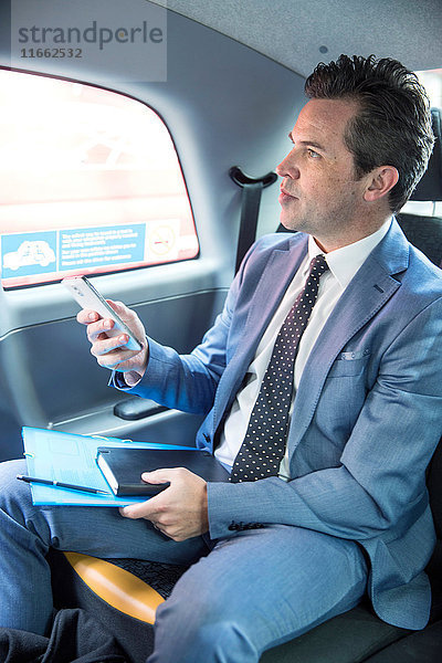 Erwachsener Geschäftsmann mit Smartphone im Taxi