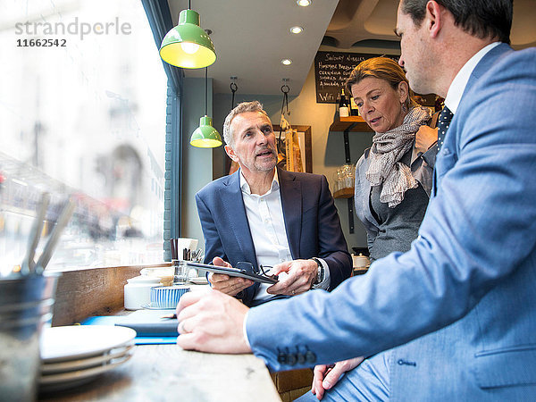 Geschäftsmänner und -frauen diskutieren im Restaurant-Fenstersitz