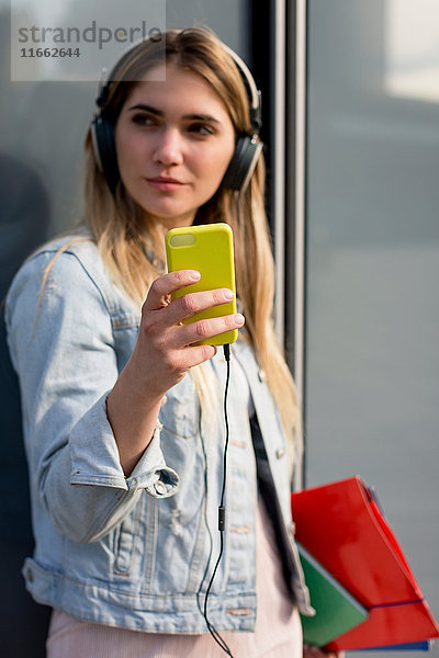 Junge Frau  im Freien  Kopfhörer tragend  Selfie mit Smartphone nehmend