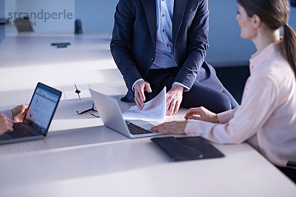 Geschäftsfrauen und -männer benutzen Laptops als Konferenztisch