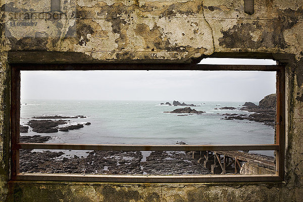 Kornisches Meer und Felsen durch ein altes Fenster gesehen.
