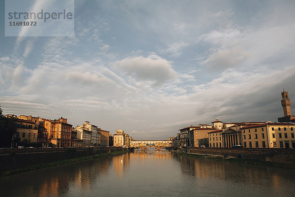 Die Ponte Vecchio und der Arno in Florenz  bei bewölktem Himmel in der Abenddämmerung. Flaches ruhiges Wasser.