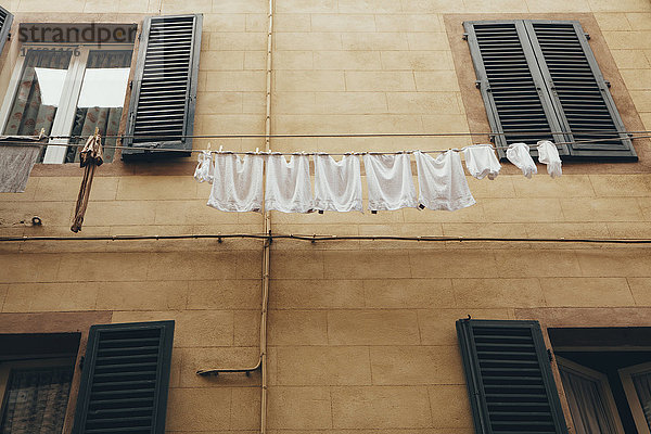 Wäsche hängt an Wäscheleinen hoch über der Straße in der historischen Stadt Siena in der Toskana