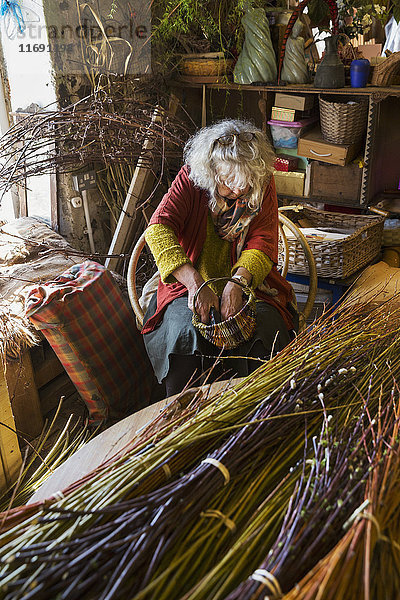Frau webt in einer Weberei einen Korb  Bündel aus Weiden.
