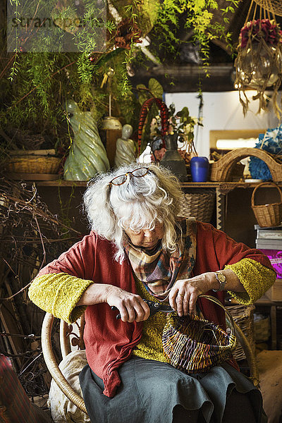 Frau webt einen Korb in einer Weberei.