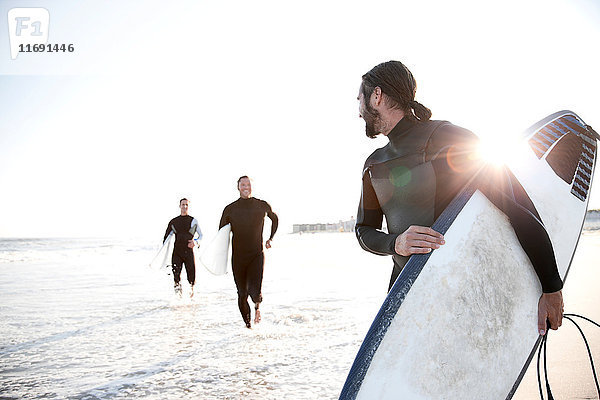 Drei Surfer am Strand