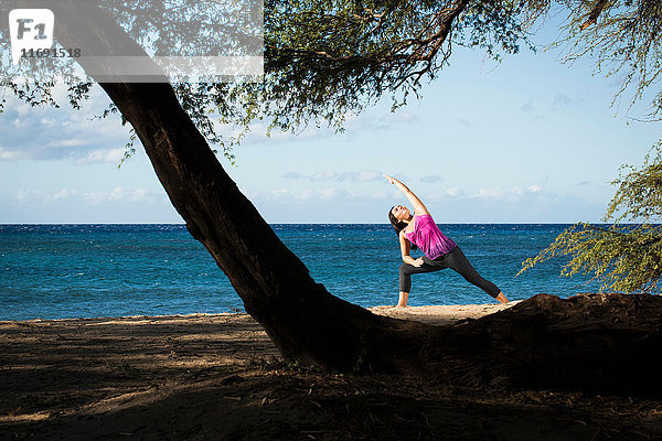 Frau praktiziert Yoga am Strand