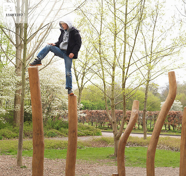Junge tritt im Park auf Holzpfähle