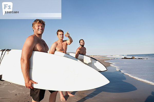 Drei Surfer am Strand