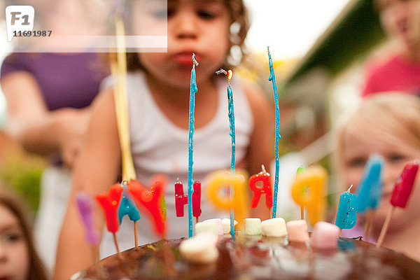 3-jähriges Mädchen bläst Kerzen auf Geburtstagskuchen aus