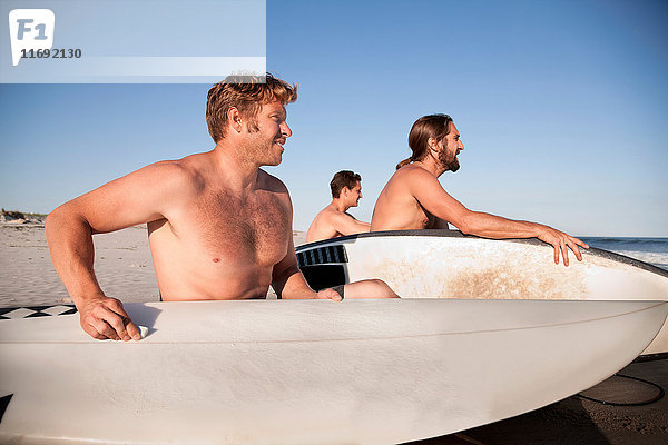 Drei Surfer am Strand