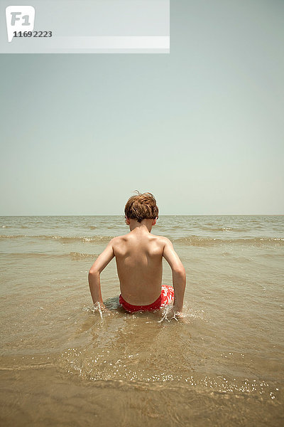 Junge spielt in Wellen am Strand