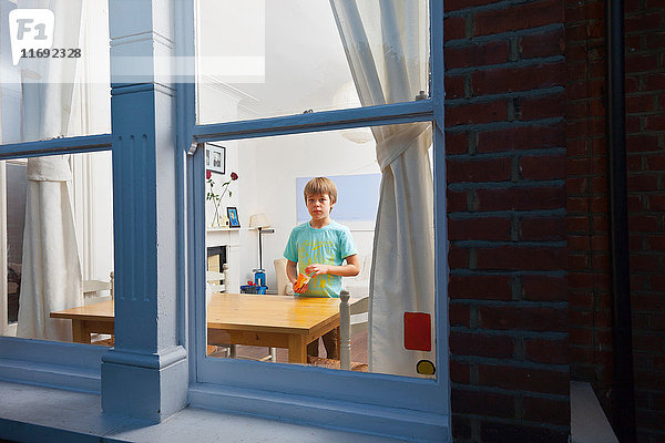 Junge im Wohnzimmer durch Fenster betrachtet