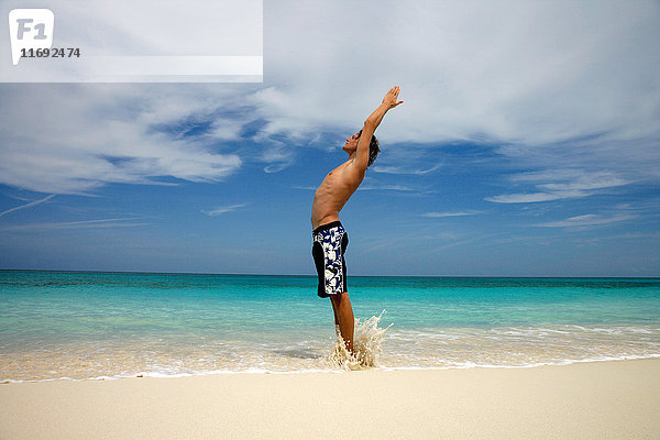 Mann praktiziert Yoga am tropischen Strand