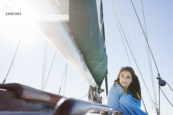 Junge brünette Frau auf einer in eine Decke gehüllten Yacht