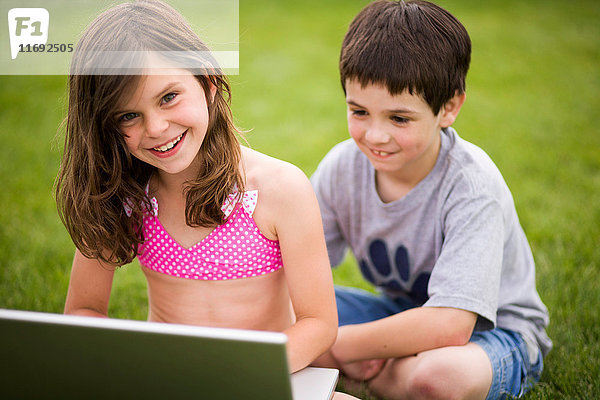 Kinder benutzen Laptop im Freien