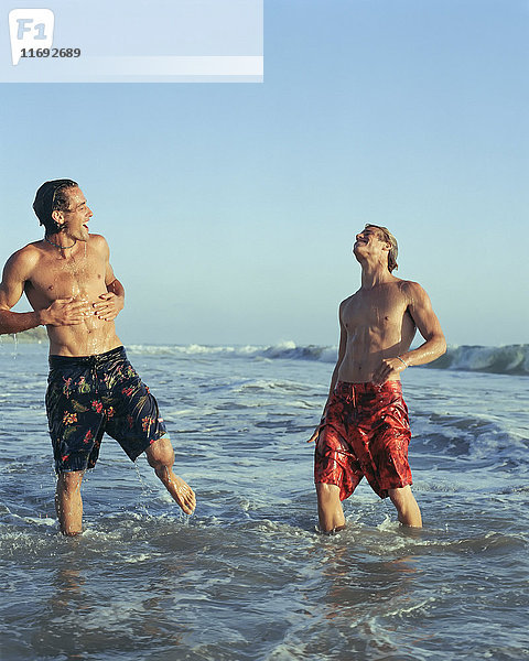 Männer spielen in Wellen am Strand