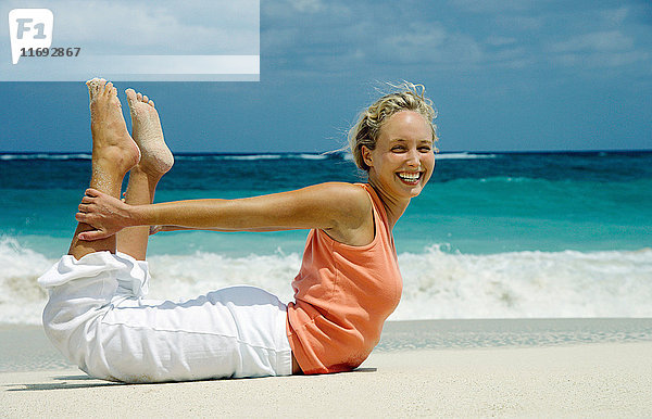 Frau praktiziert Yoga am tropischen Strand