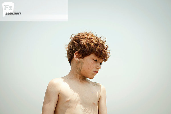 Junge mit nacktem Oberkörper im Freien stehend