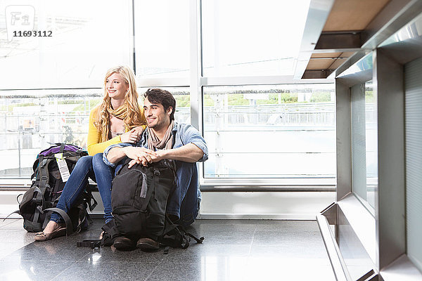 Auf dem Boden sitzendes Ehepaar im Flughafen