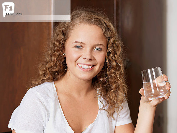 Porträt einer jungen Frau  die ein Glas Wasser hält.