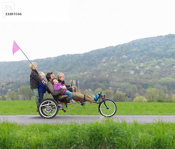 Familie fährt gemeinsam auf einem dreirädrigen Fahrrad