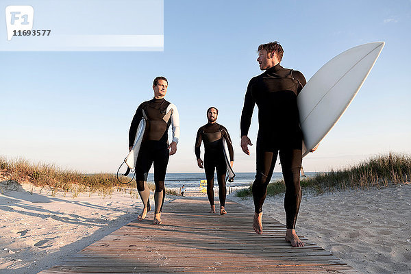 Drei Surfer auf der Strandpromenade