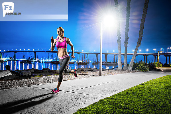 Junge Frau joggt in der Abenddämmerung