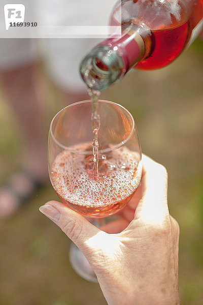 Frau schenkt Glas Wein im Freien ein