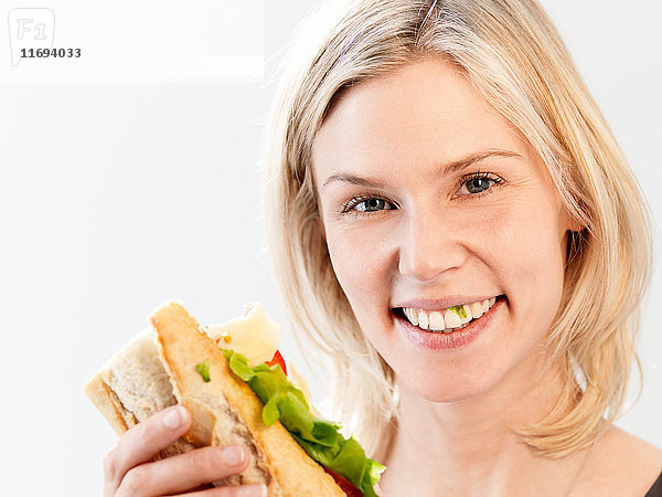 Lächelnde Frau mit Salat zwischen den Zähnen  Studioaufnahme