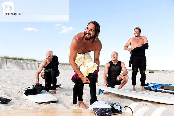 Vier Surfer ziehen sich am Strand an