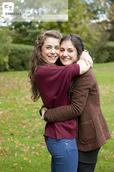 Lächelnde Mädchen umarmen sich im Park