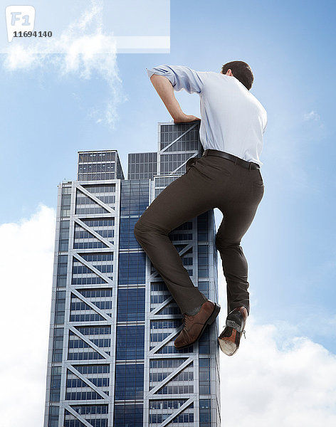 Übergroßer Geschäftsmann klettert auf Wolkenkratzer  niedriger Blickwinkel