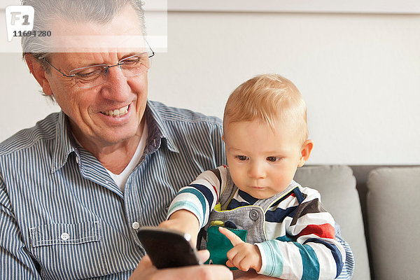 Mann mit Enkel telefoniert mit Handy