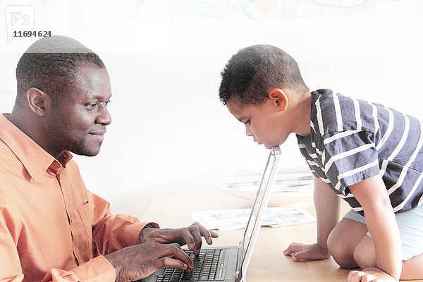 Junge beobachtet Vater bei Laptop-Nutzung