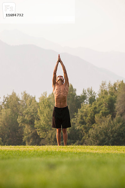 Mann praktiziert Yoga im Park