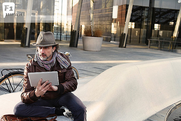 Mittelgroßer erwachsener Mann benutzt digitales Tablet in der Stadt