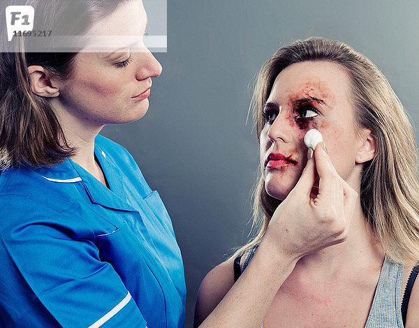 Krankenschwester reinigt Frau mit geprelltem Gesicht