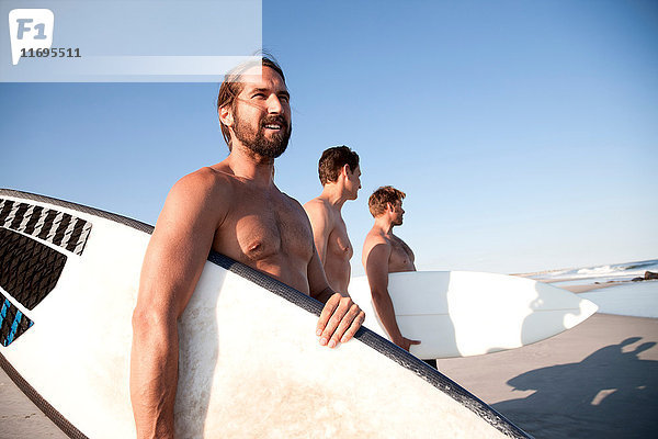 Drei Surfer am Strand