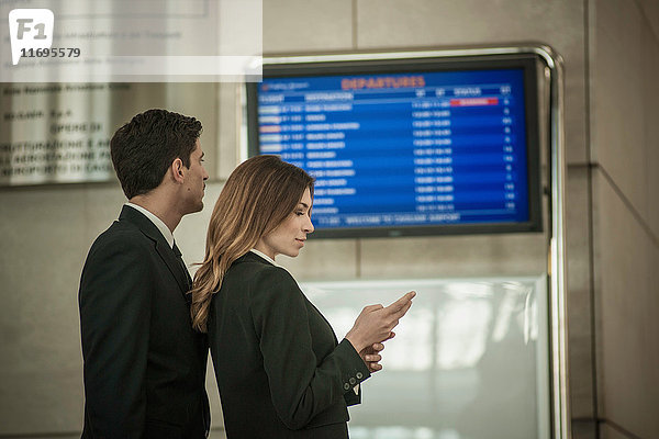 Geschäftsleute im Flughafen nach Abflugtafel