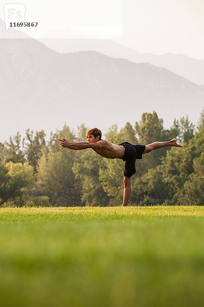 Mann praktiziert Yoga im Park