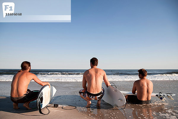 Drei Surfer am Strand