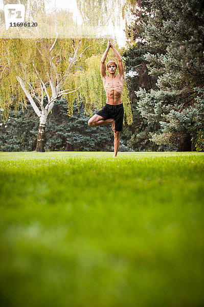 Mann praktiziert Yoga im Park