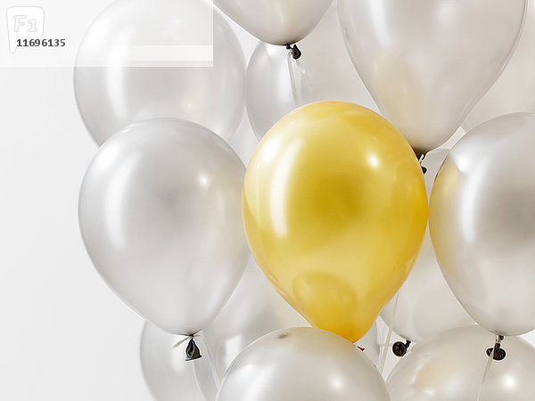 Goldener Ballon in silbernen Ballons vor weißem Hintergrund