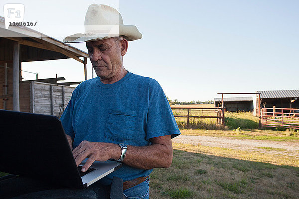 Landwirt mit Laptop in der Scheune