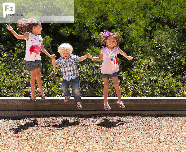 Kinder springen gemeinsam im Park