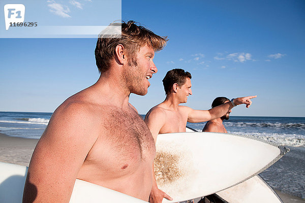 Drei Surfer am Strand