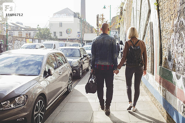 Durchgehende Rückansicht des Paares beim Gehen auf dem Bürgersteig im Stadtverkehr